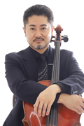 Portrait of a man in a dark suit holding a cello in front of a white background