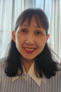 Portrait of a smiling woman with shoulder length black hair wearing a light colored collared shirt indoors